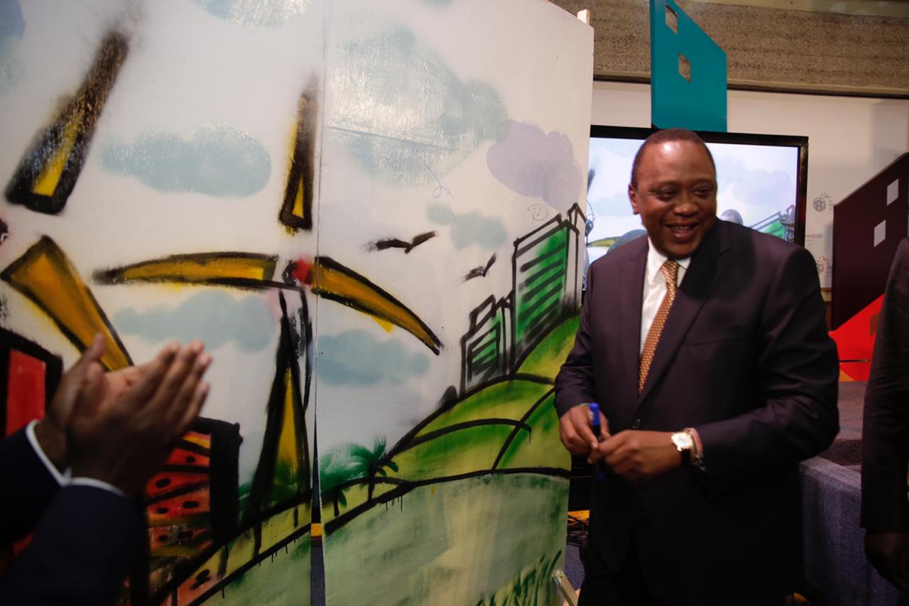 Kenya's President Uhuru Kenyatta signs a graffiti wall after the panel discussion