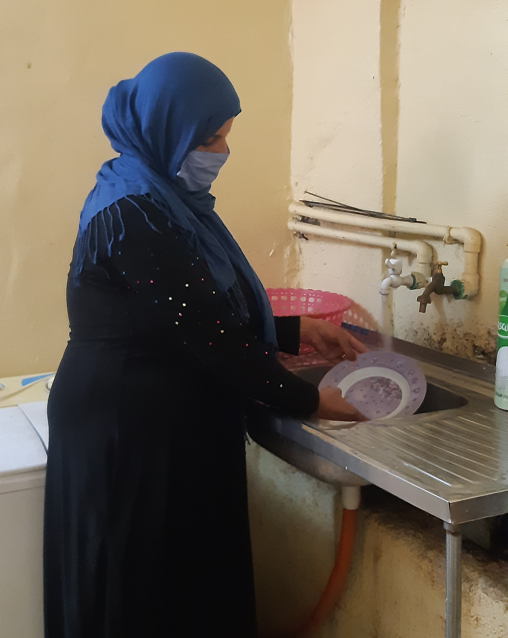 Um Medyan uses the enhanced water network to wash dishes.